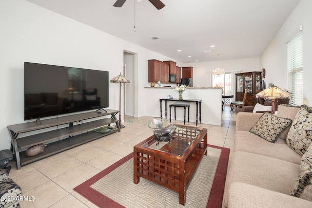 tiled living room featuring ceiling fan with notable chandelier and a wealth of natural light