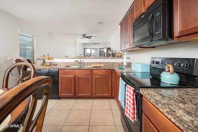 kitchen with dark stone counters, black appliances, sink, ceiling fan, and light tile patterned flooring