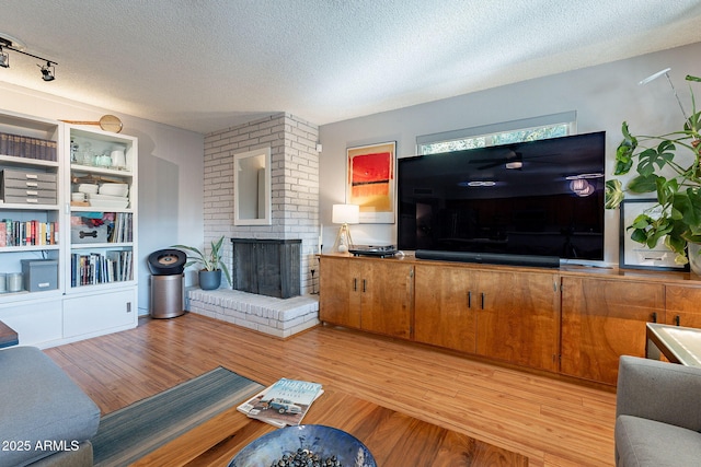 living room featuring a textured ceiling, a fireplace, and light hardwood / wood-style flooring