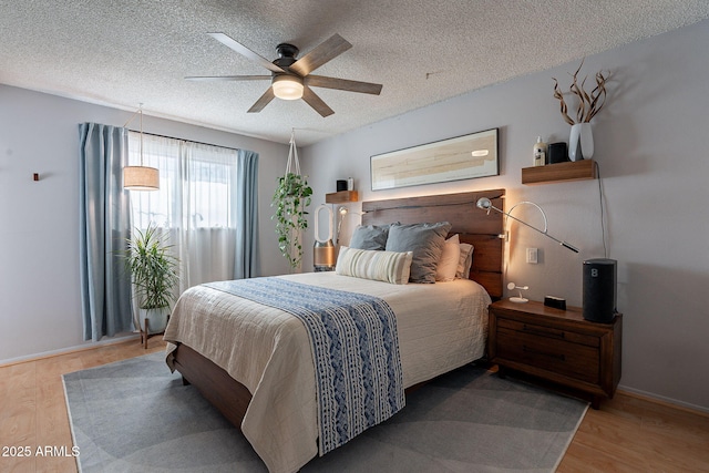 bedroom featuring ceiling fan, hardwood / wood-style floors, and a textured ceiling