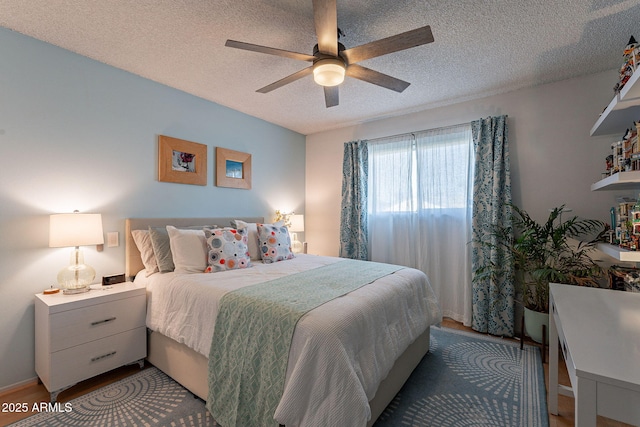 bedroom with hardwood / wood-style flooring, ceiling fan, and a textured ceiling