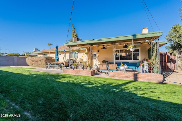 back of property with outdoor lounge area, a yard, ceiling fan, and a patio area