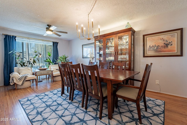 dining area with ceiling fan with notable chandelier, light hardwood / wood-style floors, and a textured ceiling