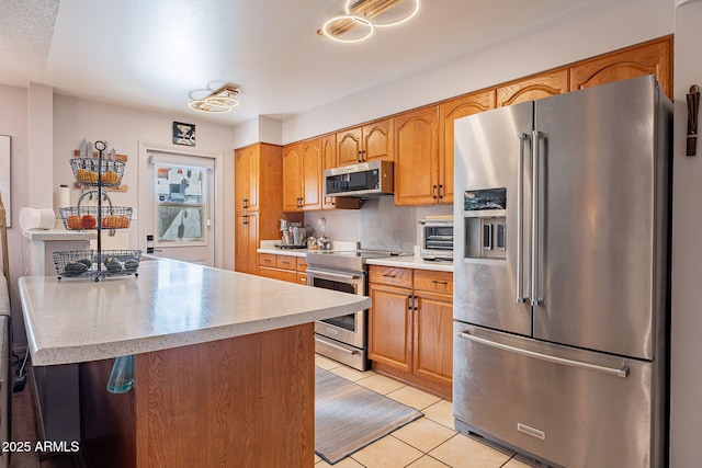 kitchen with appliances with stainless steel finishes, a center island, and light tile patterned floors