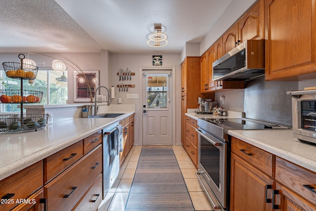 kitchen featuring light tile patterned flooring, stainless steel appliances, sink, and a textured ceiling