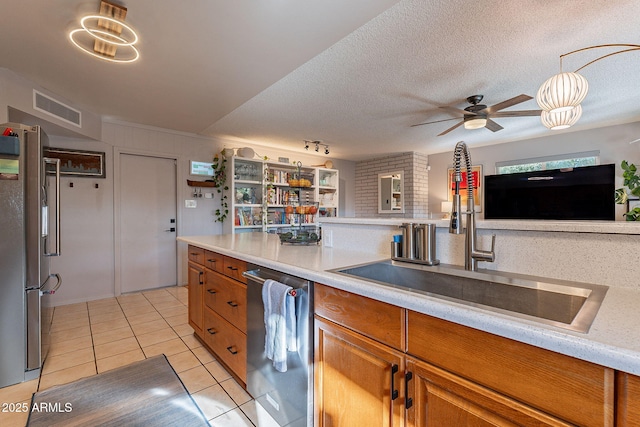 kitchen with sink, light tile patterned floors, ceiling fan, appliances with stainless steel finishes, and a textured ceiling