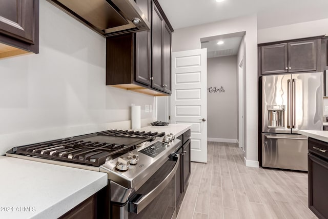 kitchen with dark brown cabinetry, ventilation hood, light hardwood / wood-style floors, and appliances with stainless steel finishes