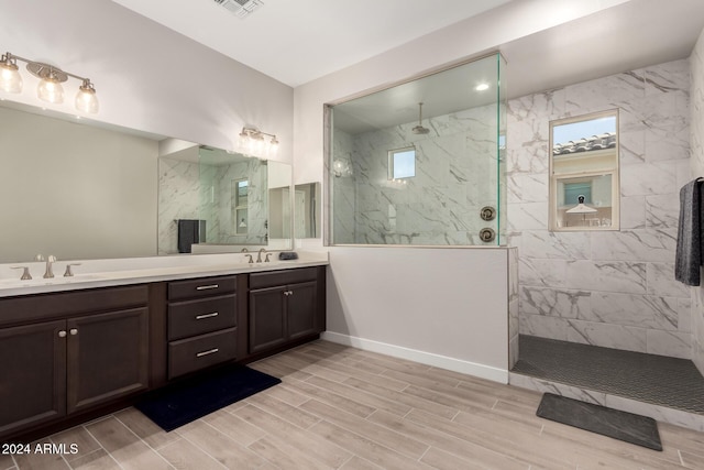 bathroom with tiled shower and vanity