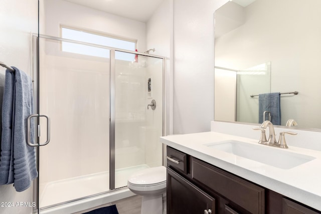 bathroom featuring vanity, toilet, and a shower with door