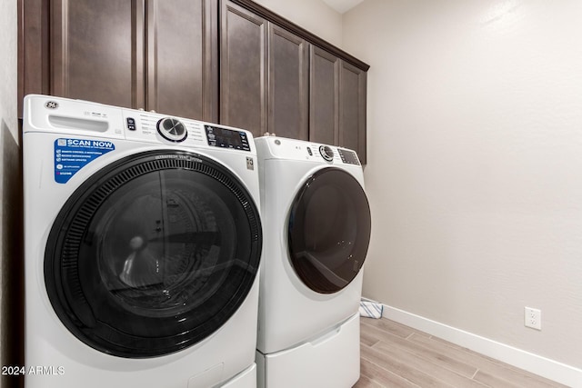 clothes washing area with cabinets, independent washer and dryer, and light hardwood / wood-style flooring