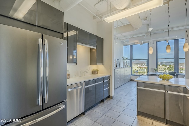 kitchen featuring light tile patterned flooring, sink, stainless steel appliances, and hanging light fixtures