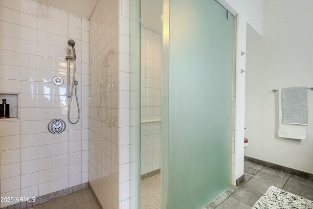 bathroom with tile patterned flooring, toilet, and a tile shower