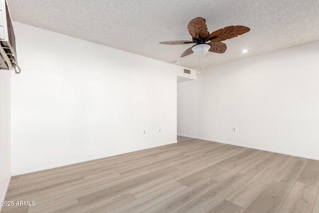 spare room with ceiling fan, a textured ceiling, and light wood-type flooring