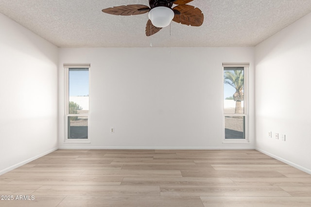 empty room featuring a healthy amount of sunlight, light hardwood / wood-style floors, and a textured ceiling