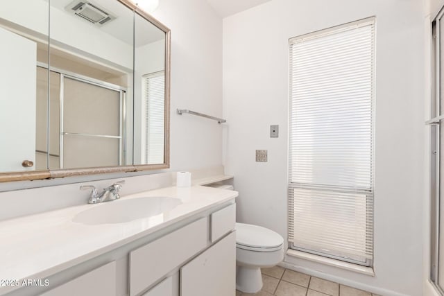 bathroom featuring tile patterned flooring, vanity, an enclosed shower, and toilet