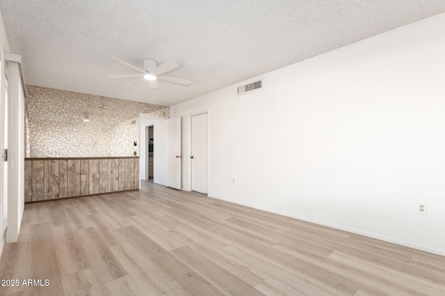 unfurnished room with ceiling fan, a textured ceiling, and light hardwood / wood-style flooring