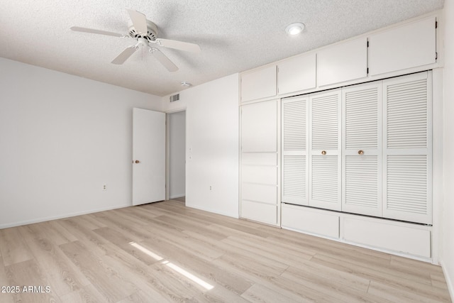 unfurnished bedroom featuring ceiling fan, light wood-type flooring, a closet, and a textured ceiling