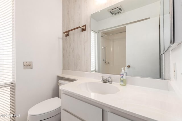 bathroom featuring walk in shower, a healthy amount of sunlight, vanity, and toilet