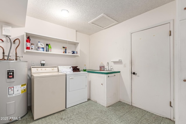 clothes washing area with washer and dryer, sink, cabinets, electric water heater, and a textured ceiling