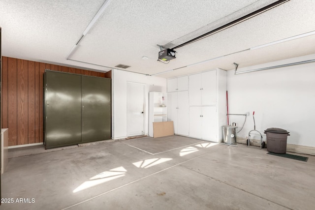 garage featuring a garage door opener and wooden walls