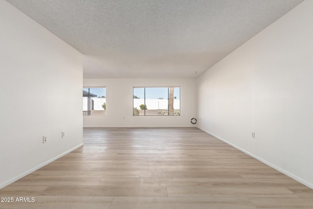 empty room with light hardwood / wood-style floors and a textured ceiling