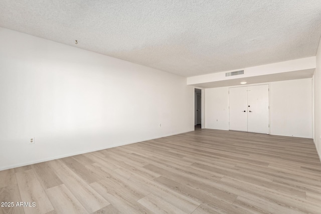 unfurnished bedroom featuring a closet, a textured ceiling, and light hardwood / wood-style flooring