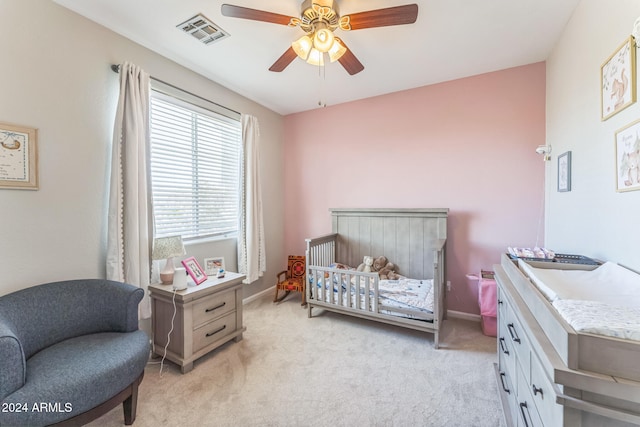 carpeted bedroom featuring ceiling fan and a nursery area