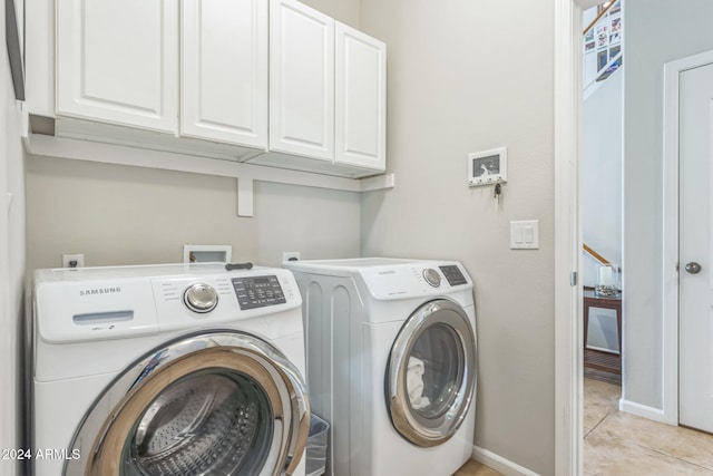 clothes washing area featuring separate washer and dryer, cabinets, and light tile patterned floors