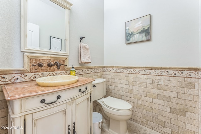 bathroom with toilet, vanity, and tile walls