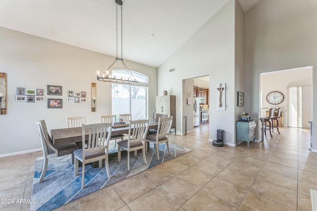 tiled dining space featuring an inviting chandelier and high vaulted ceiling