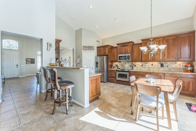 kitchen with light stone counters, appliances with stainless steel finishes, light tile patterned floors, decorative light fixtures, and a notable chandelier