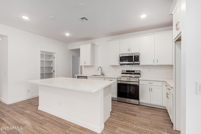 kitchen featuring sink, white cabinetry, stainless steel appliances, and a kitchen island