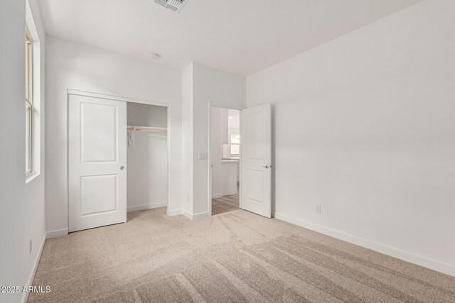 unfurnished bedroom with light carpet and a closet