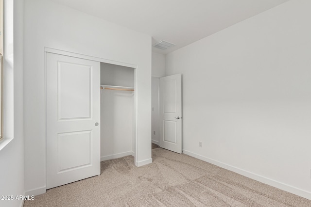 unfurnished bedroom featuring light carpet and a closet