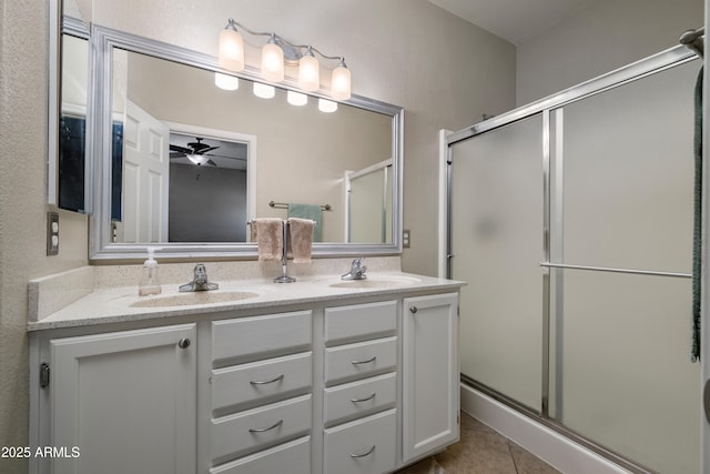 bathroom with double vanity, a ceiling fan, a stall shower, a sink, and tile patterned floors