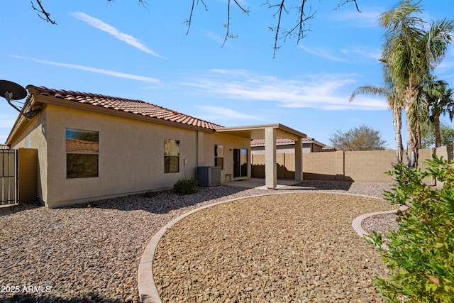 back of house with central AC unit, a fenced backyard, a tile roof, stucco siding, and a patio area