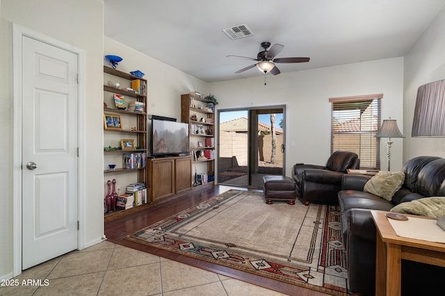 living room featuring light tile patterned floors, visible vents, and a ceiling fan