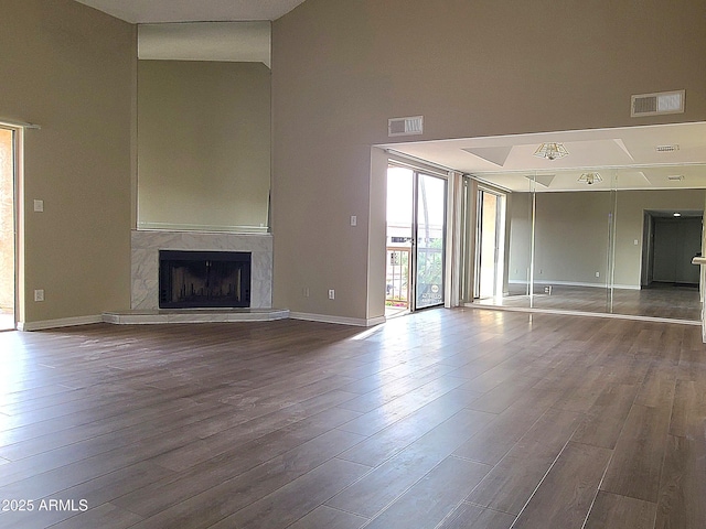 unfurnished living room featuring a fireplace, hardwood / wood-style floors, and a high ceiling