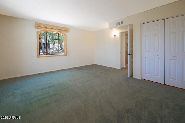 unfurnished bedroom with dark carpet and a closet