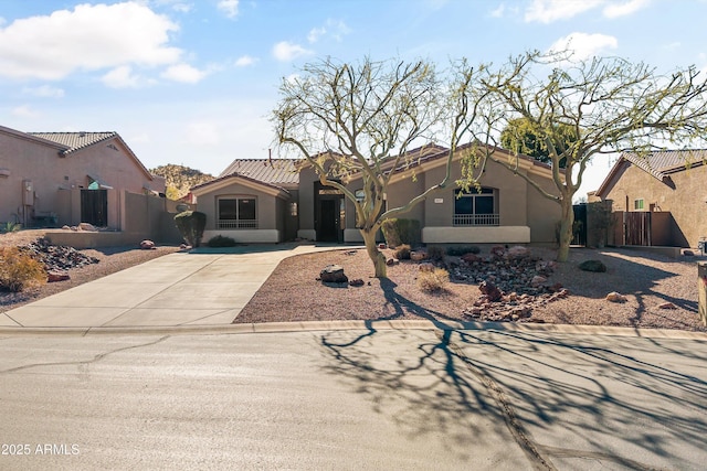 mediterranean / spanish-style home with a tile roof, fence, concrete driveway, and stucco siding