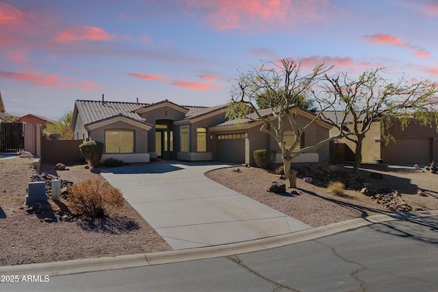 mediterranean / spanish home featuring an attached garage, fence, a tile roof, concrete driveway, and stucco siding