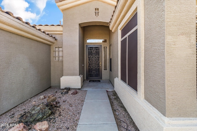 entrance to property featuring a tile roof and stucco siding