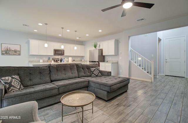 living area with light wood-type flooring, ceiling fan, visible vents, and recessed lighting