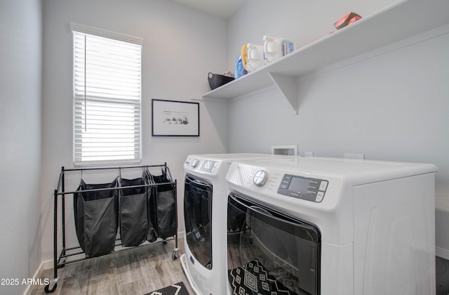clothes washing area featuring washer and dryer, laundry area, baseboards, and wood finished floors