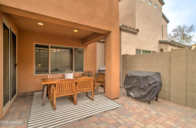 view of patio featuring a grill and fence