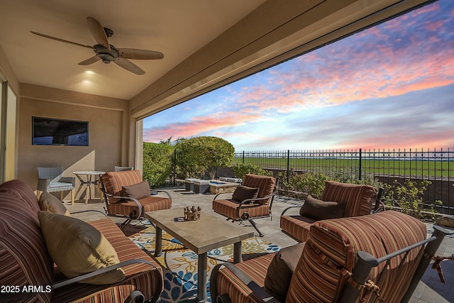 patio terrace at dusk featuring ceiling fan and an outdoor living space