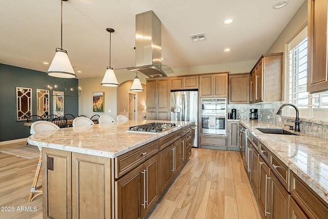 kitchen featuring appliances with stainless steel finishes, sink, a kitchen breakfast bar, island exhaust hood, and a large island