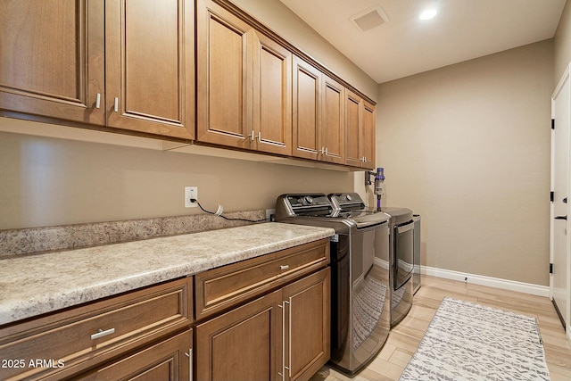 laundry room with cabinets, light wood-type flooring, and independent washer and dryer