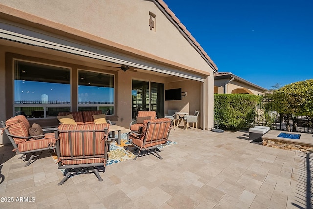 view of patio with ceiling fan and an outdoor living space with a fire pit