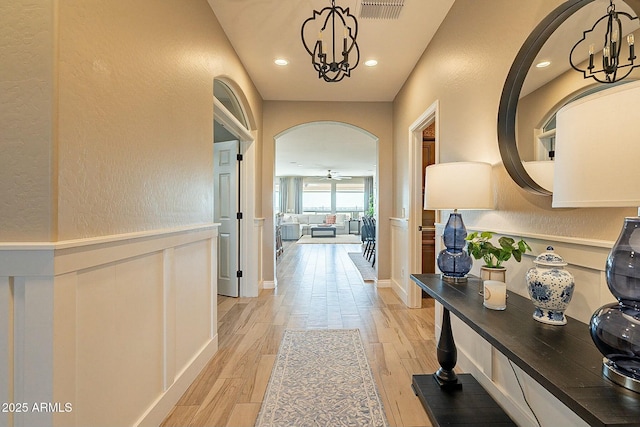 corridor with a notable chandelier and light hardwood / wood-style floors